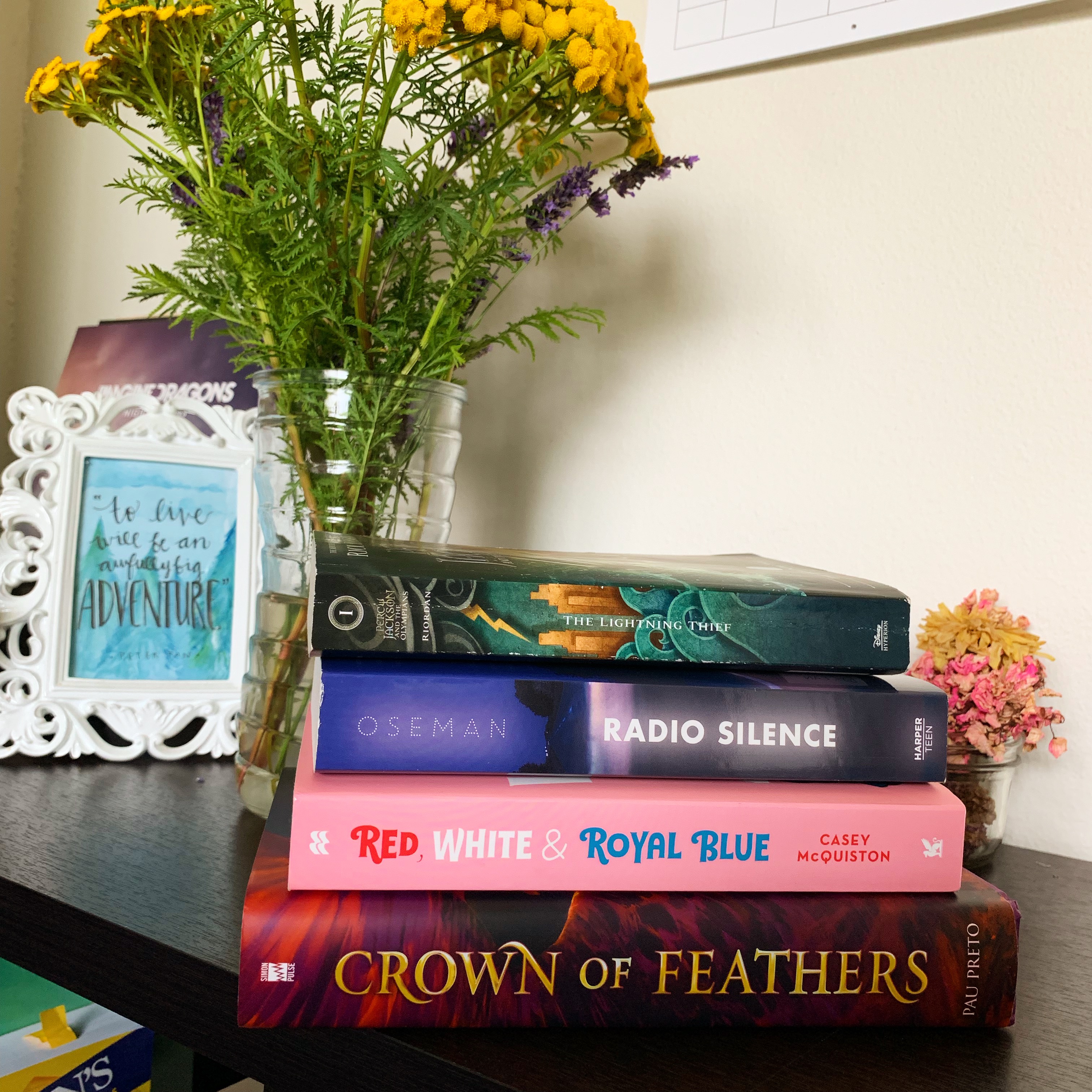 A book stack of The Lightning Thief, Radio Silence, Crown of Feathers, and Red, White & Royal Blue.